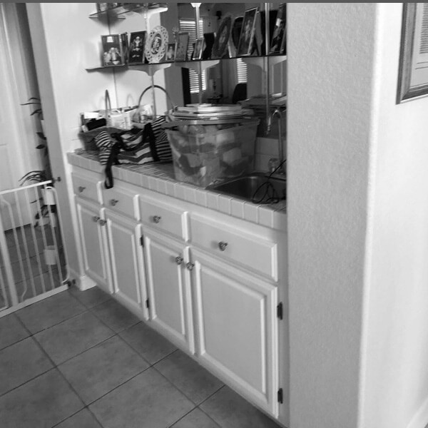 Before: Hallway storage area with dated cabinets, tiled surfaces, and open shelving